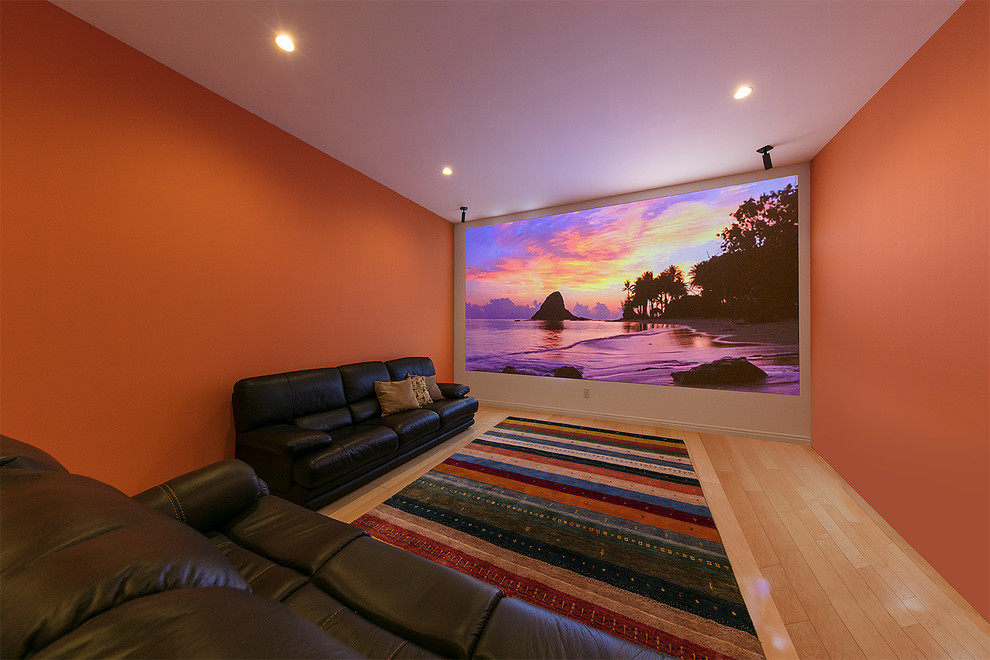 This is an example of an eclectic enclosed home theatre with orange walls, light hardwood floors, a projector screen and beige floor.