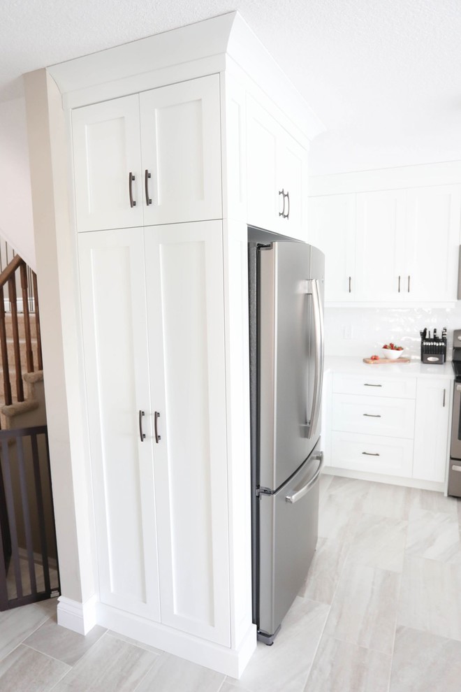 Open concept kitchen - mid-sized transitional u-shaped porcelain tile and gray floor open concept kitchen idea with a double-bowl sink, shaker cabinets, white cabinets, quartz countertops, white backsplash, ceramic backsplash, stainless steel appliances, a peninsula and white countertops