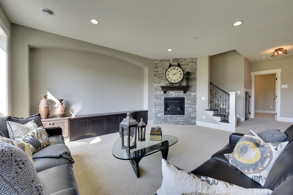 This is an example of a large transitional walk-out basement in Minneapolis with grey walls, carpet, a standard fireplace and a stone fireplace surround.