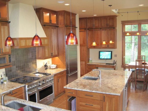 Example of a large mountain style l-shaped porcelain tile and brown floor eat-in kitchen design with an undermount sink, shaker cabinets, medium tone wood cabinets, granite countertops, stone slab backsplash, stainless steel appliances, an island and orange backsplash