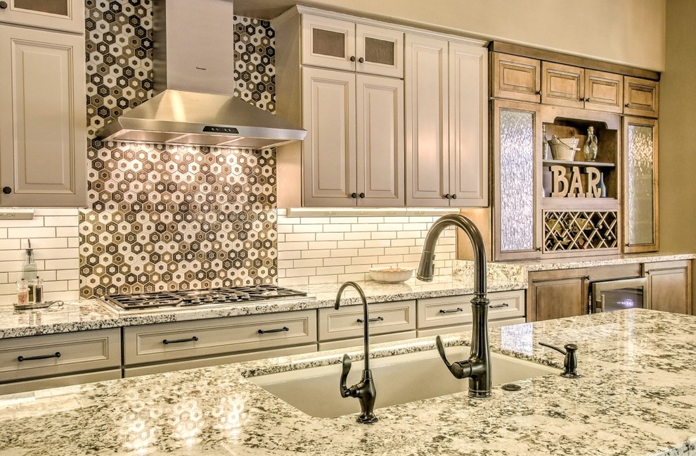 Example of a mid-sized eclectic porcelain tile and brown floor eat-in kitchen design in Phoenix with an undermount sink, raised-panel cabinets, white cabinets, granite countertops, white backsplash, ceramic backsplash, stainless steel appliances, an island and white countertops