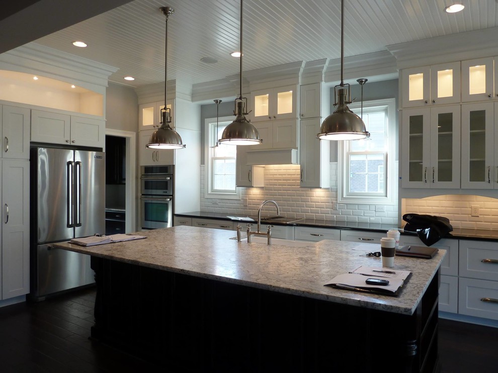 Transitional l-shaped eat-in kitchen photo in Indianapolis with a farmhouse sink, shaker cabinets, white cabinets, granite countertops, white backsplash, subway tile backsplash, stainless steel appliances and an island