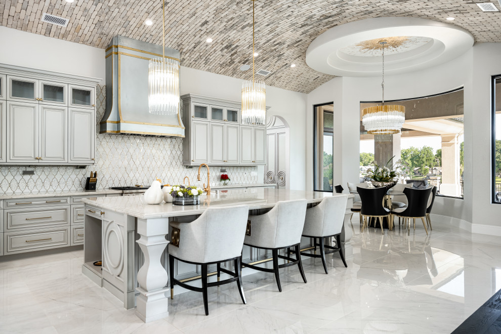 Expansive modern galley eat-in kitchen in Phoenix with a farmhouse sink, recessed-panel cabinets, white cabinets, marble benchtops, white splashback, stone tile splashback, black appliances, marble floors, with island, white floor and white benchtop.