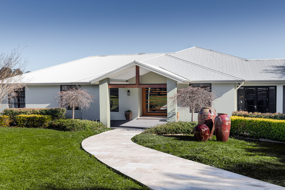 This is an example of a contemporary one-storey white house exterior in Central Coast with a hip roof and a metal roof.