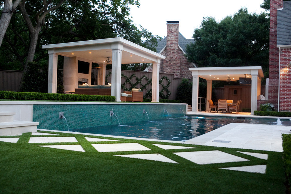 Mid-sized transitional backyard l-shaped pool in Dallas with a water feature and natural stone pavers.