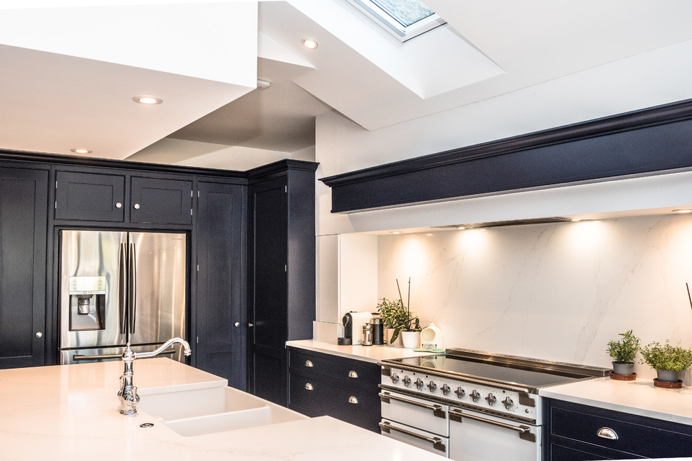 This is an example of a mid-sized contemporary u-shaped open plan kitchen in London with an undermount sink, blue cabinets, granite benchtops, white splashback, ceramic floors, with island, grey floor and white benchtop.