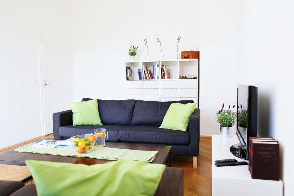 Mittelgroßes, Abgetrenntes Skandinavisches Wohnzimmer mit weißer Wandfarbe, braunem Holzboden und freistehendem TV in Frankfurt am Main