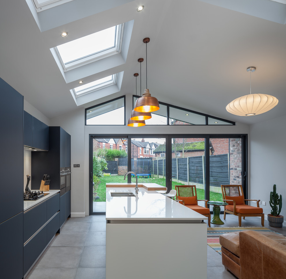 Inspiration for a mid-sized contemporary galley eat-in kitchen in Manchester with a drop-in sink, flat-panel cabinets, grey cabinets, wood benchtops, white splashback, subway tile splashback, cement tiles, with island and grey floor.