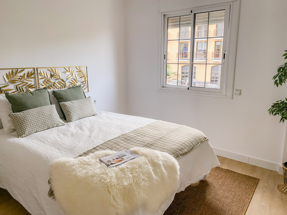 Diseño de dormitorio principal grande con paredes blancas, suelo de madera en tonos medios y suelo beige