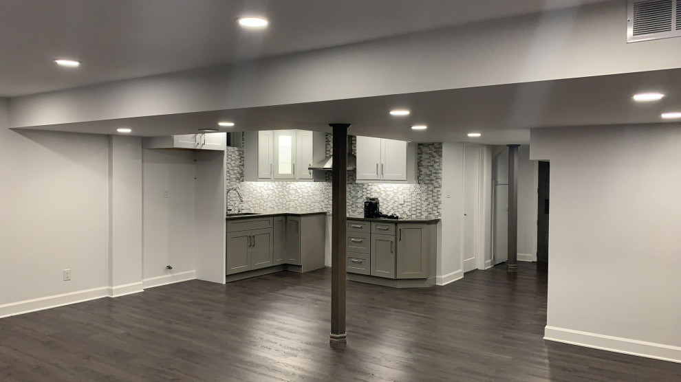 Design ideas for a large traditional walk-out basement in Toronto with a game room, grey walls, vinyl floors, a hanging fireplace, a stone fireplace surround, grey floor, recessed and panelled walls.