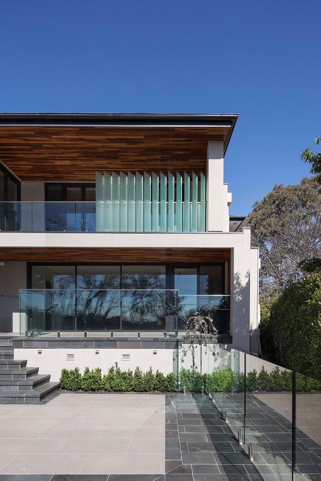 This is an example of a large contemporary two-storey stucco beige exterior in Melbourne with a hip roof.