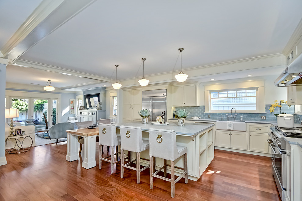 Inspiration for a large transitional l-shaped open plan kitchen in San Diego with a farmhouse sink, shaker cabinets, white cabinets, concrete benchtops, blue splashback, ceramic splashback, stainless steel appliances, medium hardwood floors and with island.