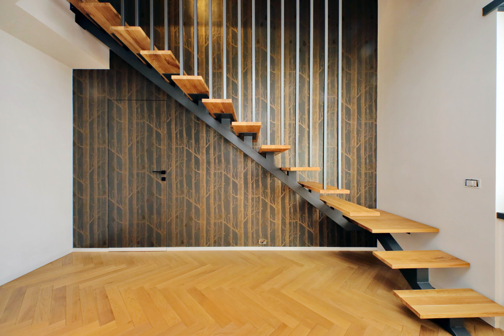 На фото: деревянная лестница в современном стиле с металлическими перилами и обоями на стенах