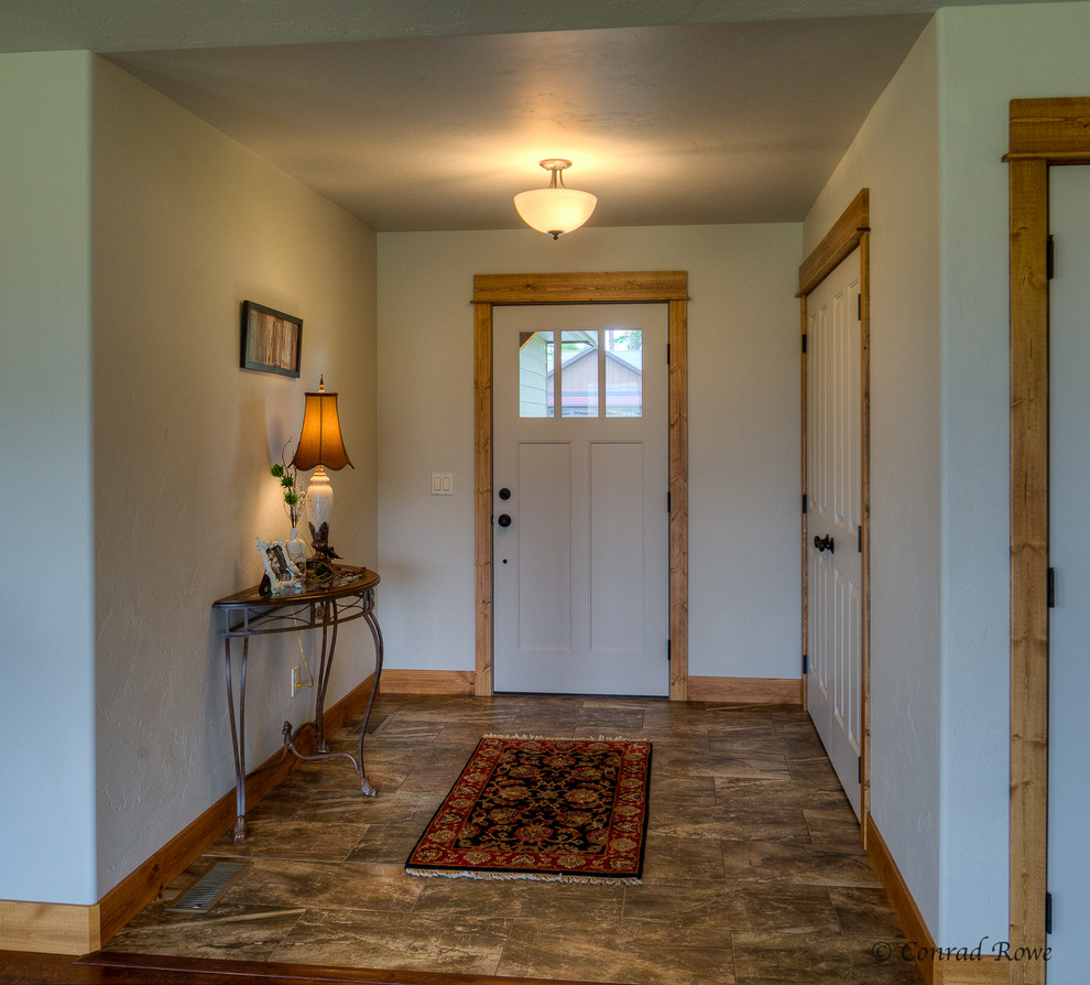 Example of a mid-sized mountain style ceramic tile front door design with white walls and a white front door