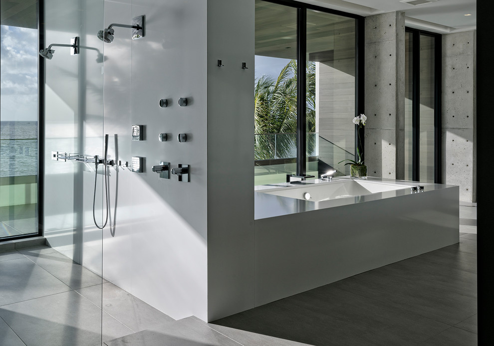 This is an example of a large modern master bathroom in Miami with flat-panel cabinets, an undermount tub, an alcove shower, a one-piece toilet, gray tile, grey walls, ceramic floors, an undermount sink, solid surface benchtops, grey floor and a hinged shower door.