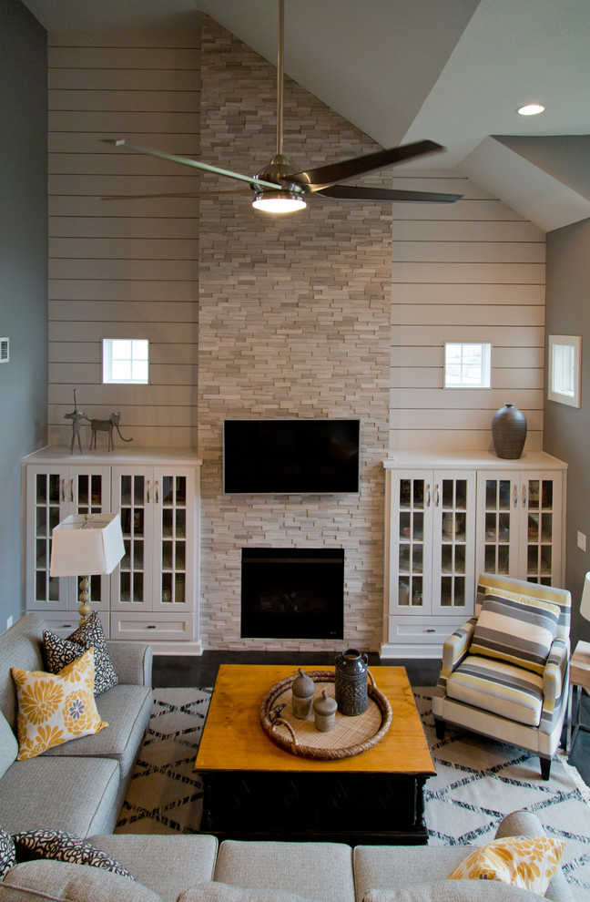 Photo of a large contemporary open concept living room in Kansas City with grey walls, dark hardwood floors, a standard fireplace, a stone fireplace surround, a wall-mounted tv and brown floor.