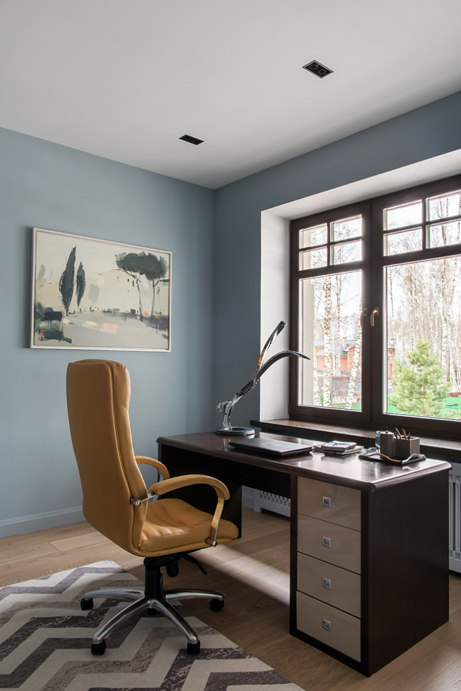 Idée de décoration pour un bureau design de taille moyenne avec un mur bleu, un sol en bois brun, un bureau intégré et un sol beige.