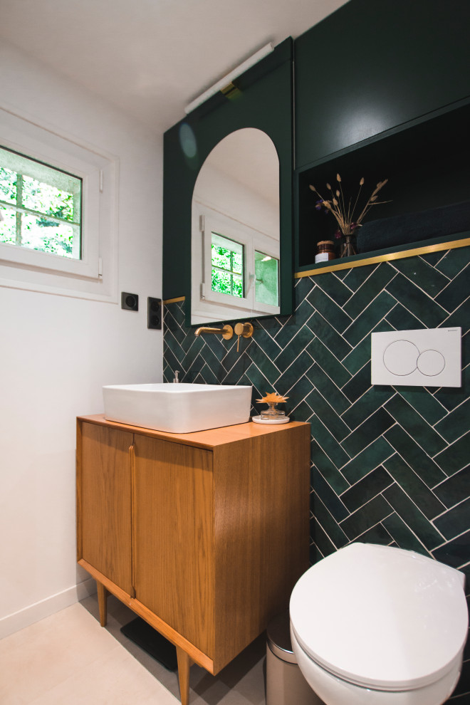 На фото: туалет в стиле ретро с инсталляцией, зеленой плиткой, зелеными стенами, раковиной с несколькими смесителями, зеленой столешницей и напольной тумбой с