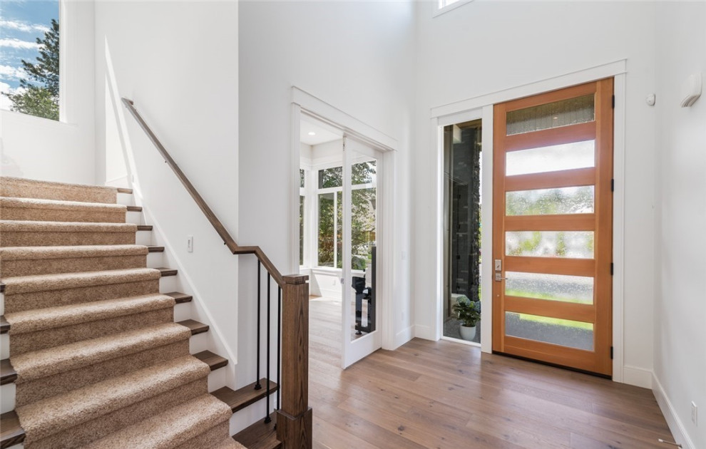 Mittelgroße Moderne Haustür mit weißer Wandfarbe, braunem Holzboden, Drehtür, oranger Haustür und gewölbter Decke in Seattle