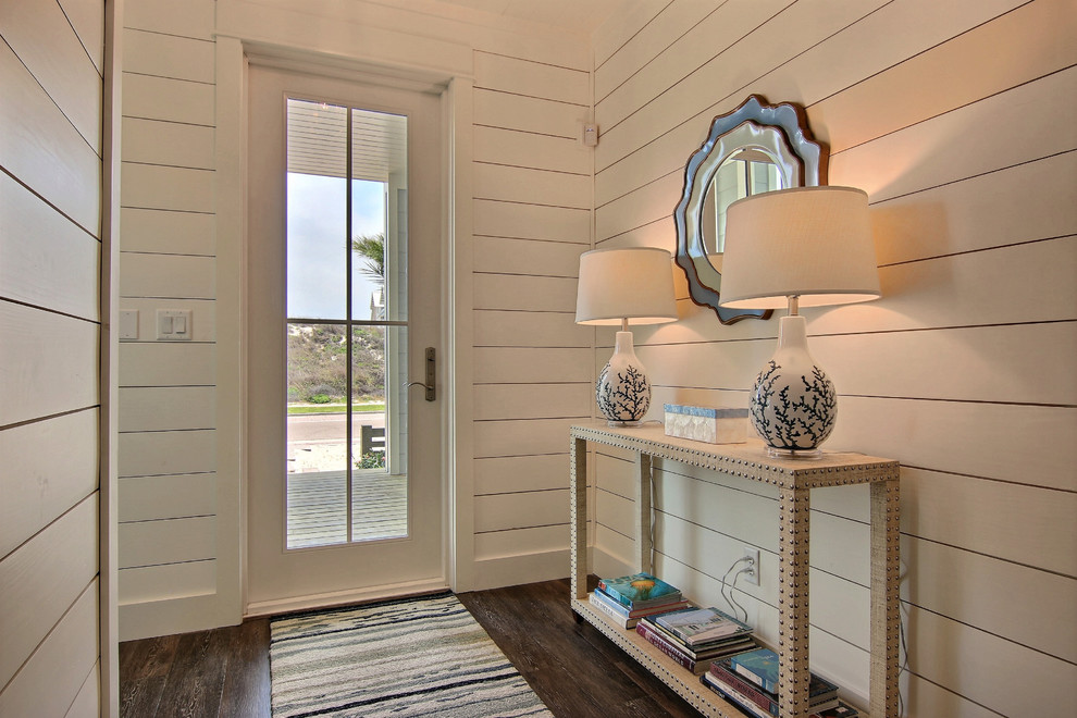 Photo of a beach style entry hall in Austin with dark hardwood floors, a single front door, brown floor and white walls.