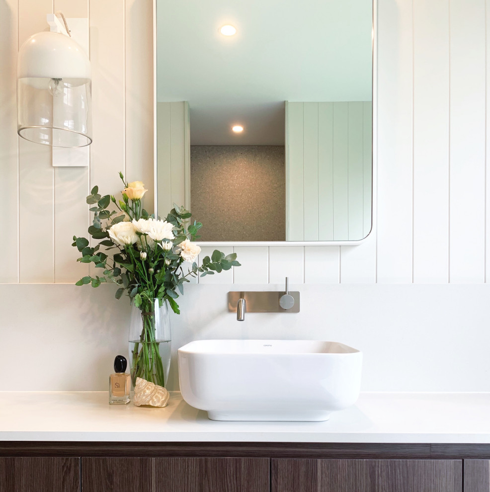 Inspiration for a mid-sized master bathroom in Brisbane with brown cabinets, a freestanding tub, an open shower, a one-piece toilet, gray tile, cement tile, white walls, cement tiles, a vessel sink, engineered quartz benchtops, grey floor, an open shower, white benchtops, a double vanity, a floating vanity and panelled walls.