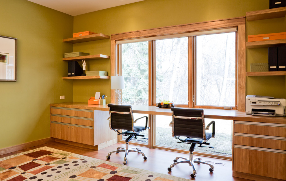 Photo of a contemporary home office in Minneapolis with a built-in desk and green walls.