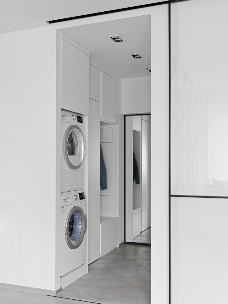 Inspiration for a contemporary utility room in Moscow with a stacked washer and dryer and grey floors.