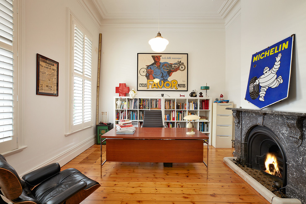 Large traditional study room in Melbourne with white walls, medium hardwood floors, a standard fireplace and a freestanding desk.