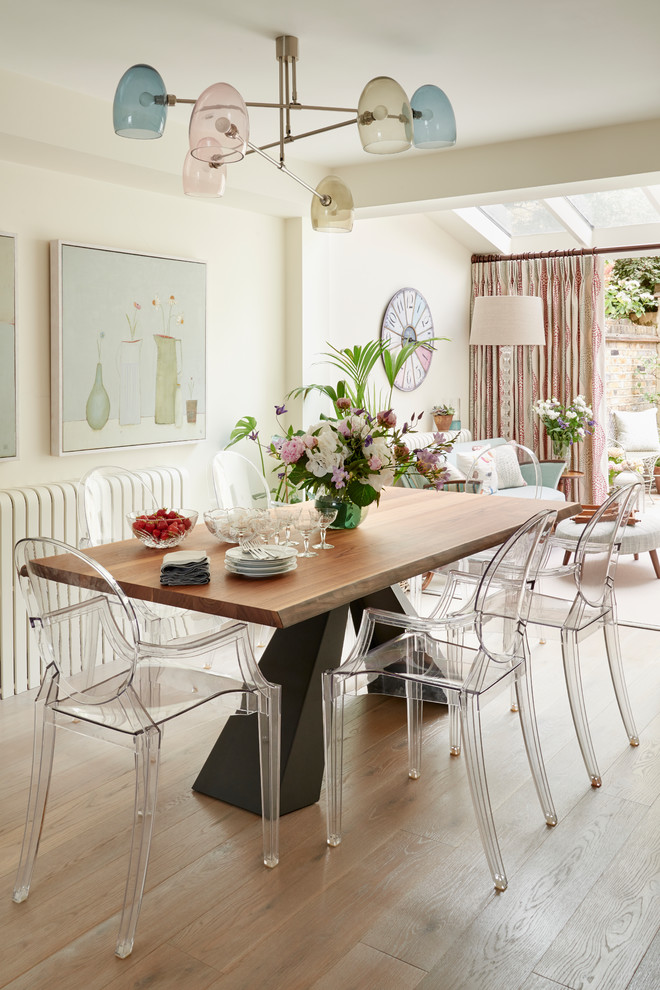 Photo of a mid-sized eclectic open plan dining in London with beige walls and light hardwood floors.