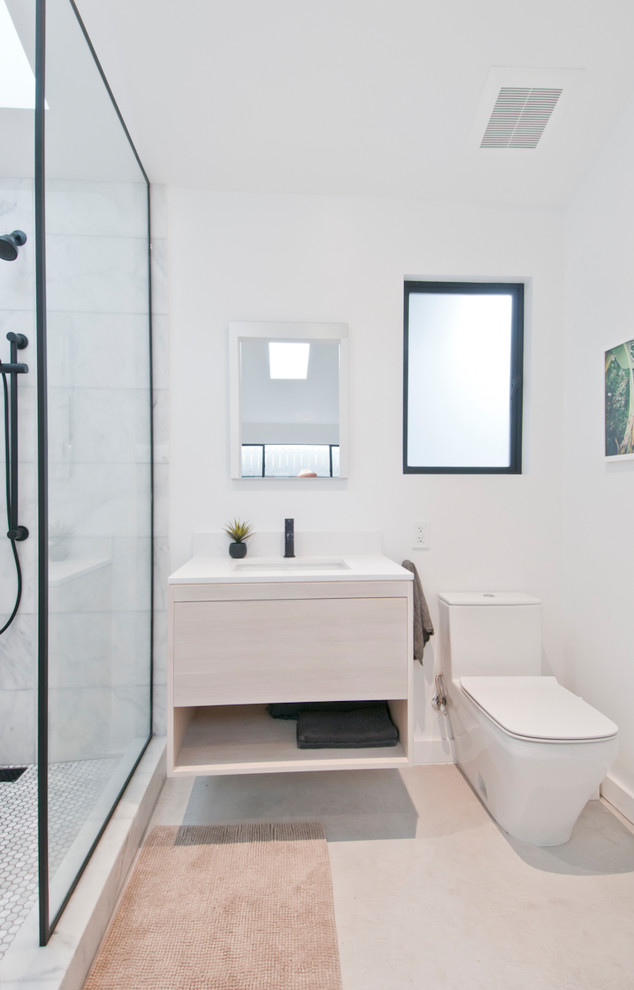 This is an example of a small modern master bathroom in Los Angeles with flat-panel cabinets, light wood cabinets, an open shower, a one-piece toilet, white tile, marble, white walls, concrete floors, a drop-in sink, engineered quartz benchtops, grey floor, an open shower and white benchtops.