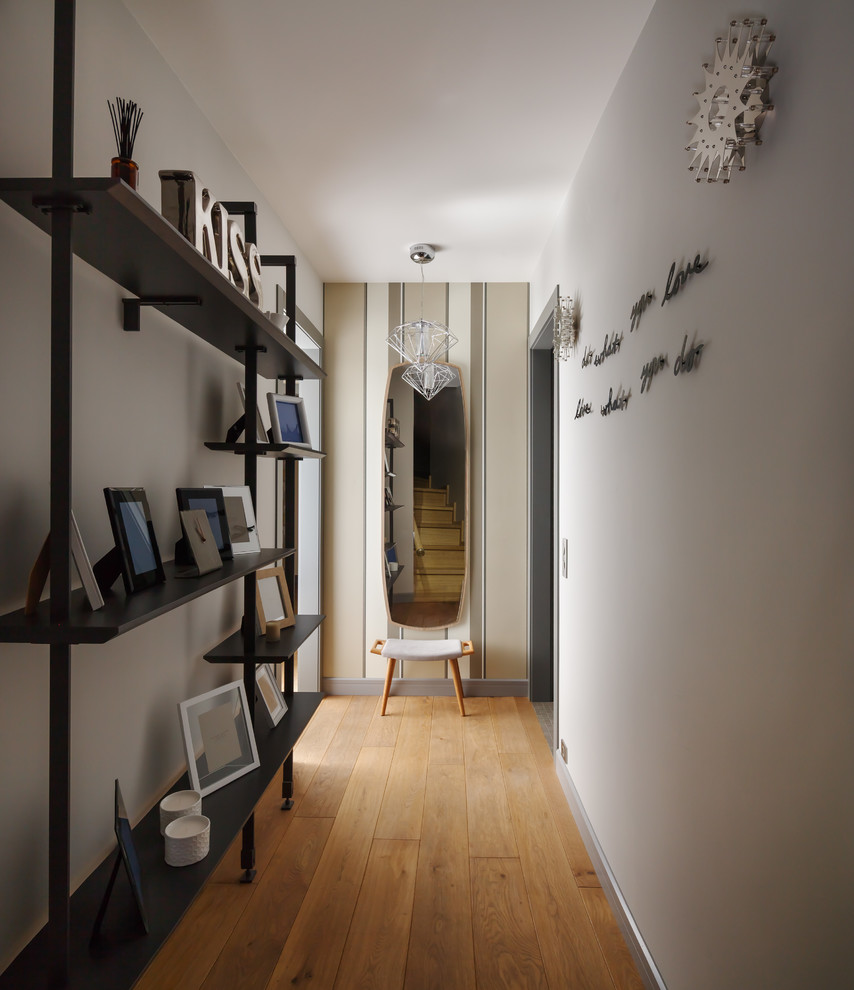This is an example of a contemporary hallway in Moscow with white walls and medium hardwood floors.