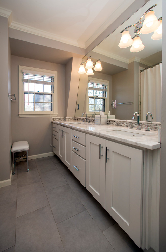 This is an example of a mid-sized transitional kids bathroom in Birmingham with shaker cabinets, white cabinets, an alcove tub, a shower/bathtub combo, white tile, ceramic tile, grey walls, porcelain floors, an undermount sink and marble benchtops.