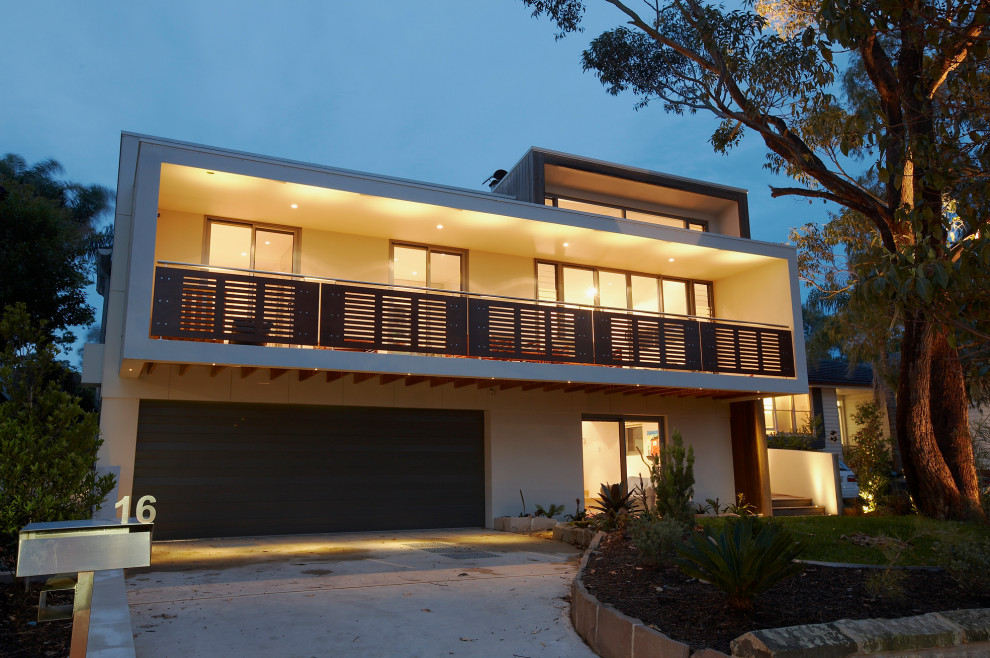 Large contemporary two-storey white house exterior in Sydney with mixed siding, a butterfly roof and a metal roof.