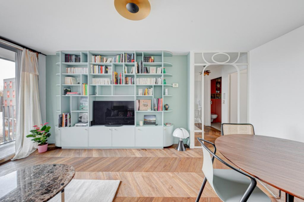 Aménagement d'une petite salle de séjour moderne ouverte avec une bibliothèque ou un coin lecture, un mur vert, parquet clair, aucune cheminée, un téléviseur encastré, un sol beige et poutres apparentes.