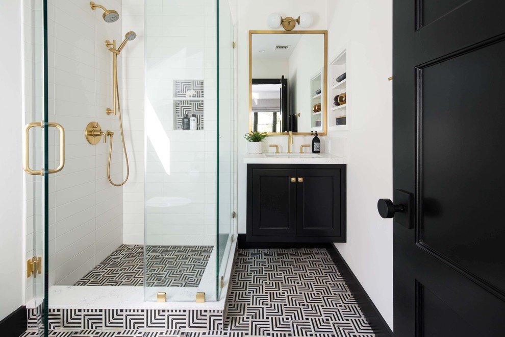 Photo of a mid-sized transitional 3/4 bathroom in Los Angeles with shaker cabinets, black cabinets, a corner shower, a one-piece toilet, white tile, porcelain tile, white walls, marble floors, a drop-in sink, engineered quartz benchtops, black floor, a hinged shower door and white benchtops.
