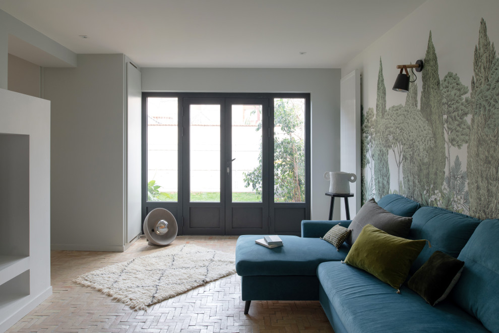 Mittelgroßes, Offenes Mediterranes Wohnzimmer mit grauer Wandfarbe, Terrakottaboden, Kaminumrandung aus Beton, Multimediawand, beigem Boden und Tapetenwänden in Lyon