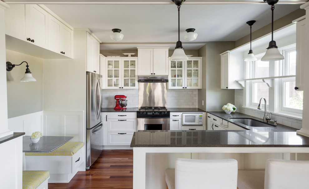 Photo of an arts and crafts u-shaped kitchen in Seattle with recycled glass benchtops, a single-bowl sink, glass-front cabinets, white cabinets, white splashback, subway tile splashback and stainless steel appliances.