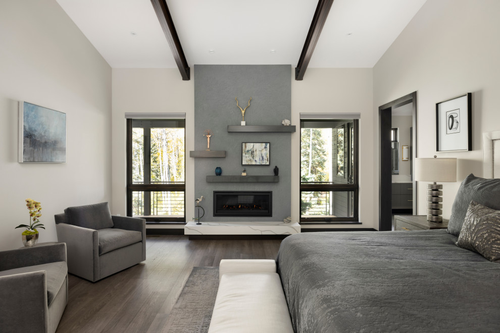 Стильный дизайн: хозяйская спальня в современном стиле с серыми стенами, паркетным полом среднего тона, стандартным камином, фасадом камина из бетона, серым полом и балками на потолке - последний тренд