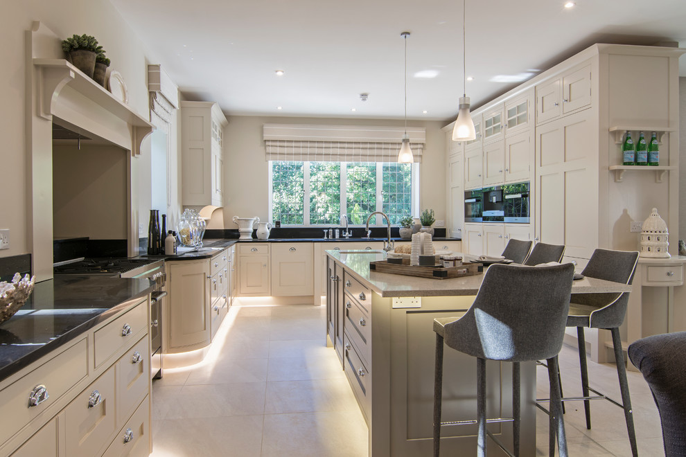 Photo of a large transitional u-shaped kitchen in Buckinghamshire with an undermount sink, shaker cabinets, beige cabinets, granite benchtops, with island, beige floor and black benchtop.