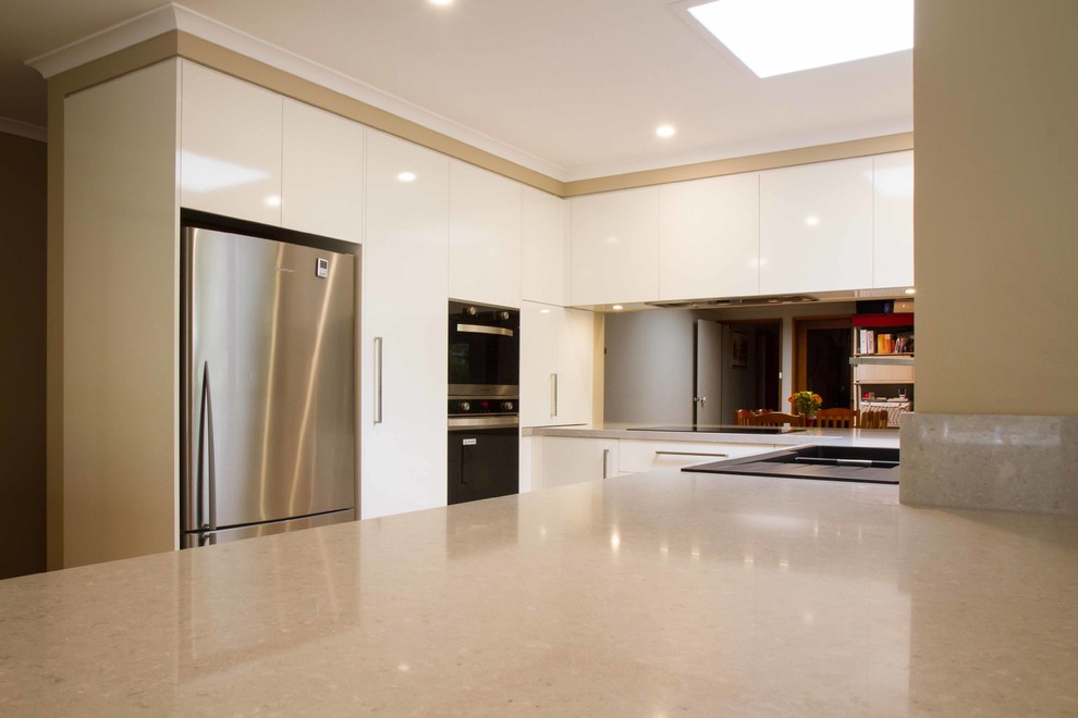 Contemporary u-shaped eat-in kitchen in Melbourne with flat-panel cabinets, white cabinets, quartz benchtops and with island.
