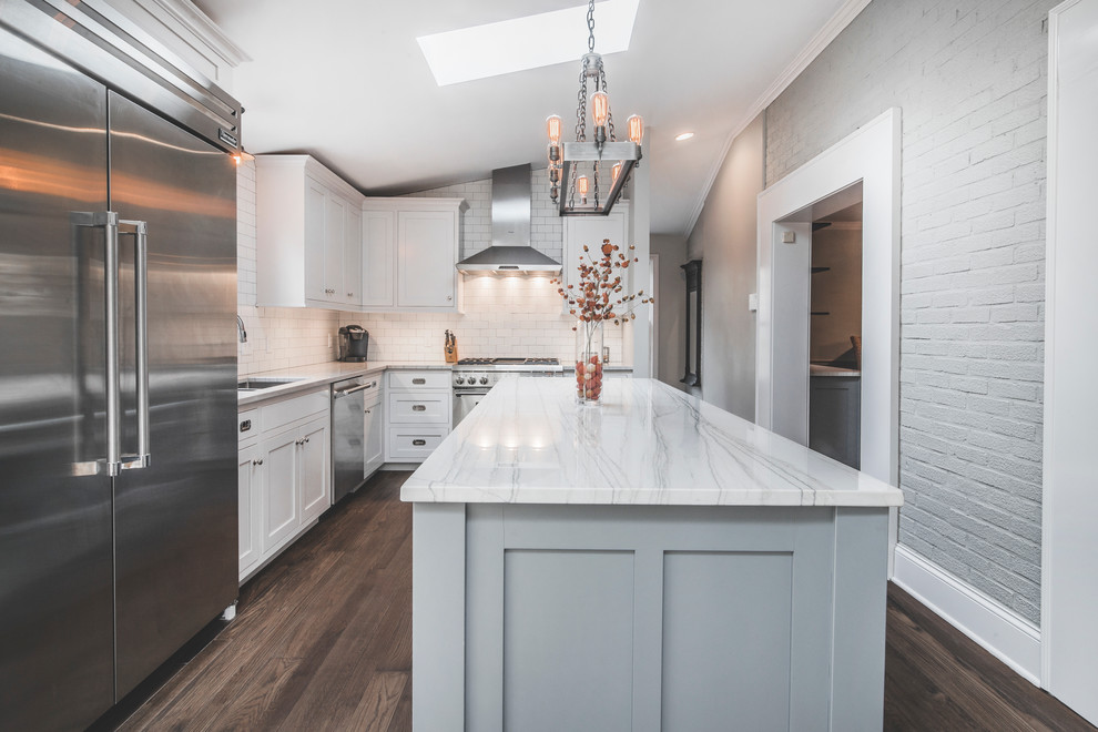 Design ideas for a large transitional l-shaped eat-in kitchen in Columbus with an undermount sink, quartzite benchtops, white splashback, with island, shaker cabinets, white cabinets, subway tile splashback, stainless steel appliances, dark hardwood floors and brown floor.