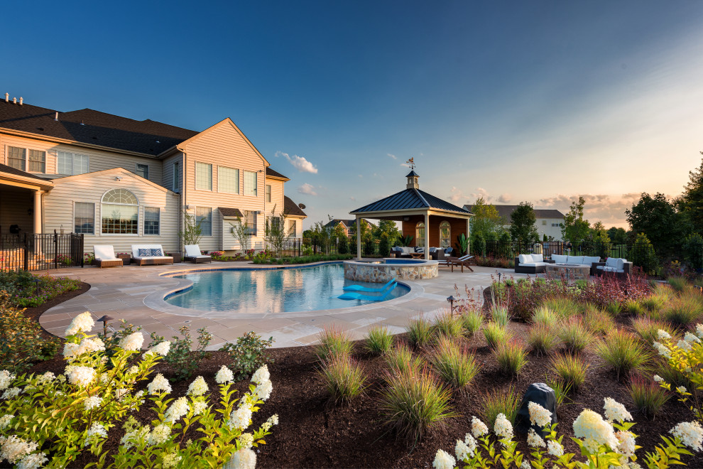 Ispirazione per una grande piscina naturale classica personalizzata dietro casa con paesaggistica bordo piscina e pavimentazioni in pietra naturale
