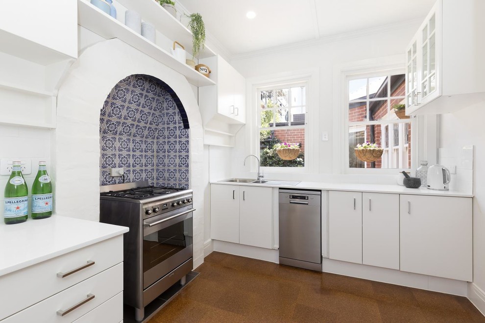 Inspiration for a small transitional l-shaped separate kitchen in Melbourne with a drop-in sink, flat-panel cabinets, white cabinets, quartz benchtops, blue splashback, ceramic splashback, stainless steel appliances, cork floors and white benchtop.