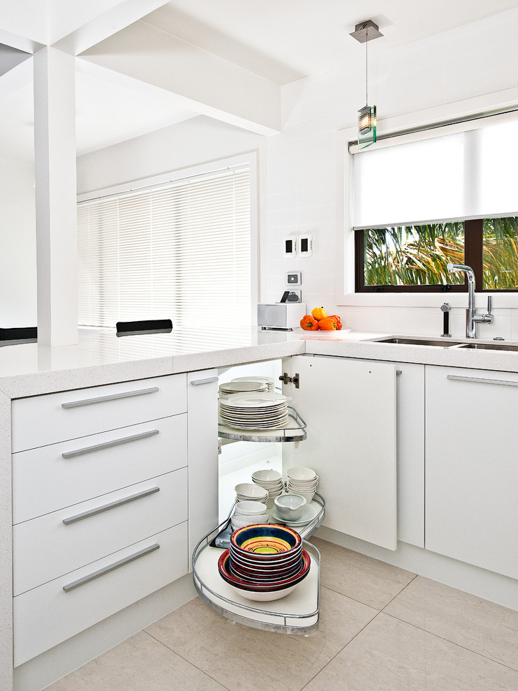 Design ideas for a mid-sized contemporary u-shaped eat-in kitchen in Auckland with an undermount sink, white cabinets, stainless steel appliances, ceramic floors, flat-panel cabinets, quartz benchtops, white splashback, subway tile splashback, a peninsula and beige floor.