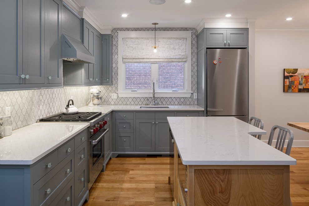 Design ideas for a mid-sized transitional l-shaped eat-in kitchen in Ottawa with an undermount sink, recessed-panel cabinets, quartzite benchtops, grey splashback, stone tile splashback, stainless steel appliances, with island, grey cabinets and medium hardwood floors.