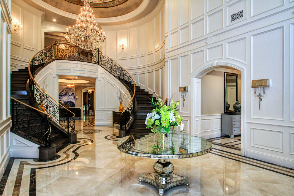 Photo of an expansive traditional foyer in Los Angeles with white walls and marble floors.