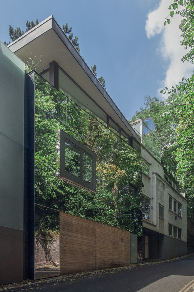 This is an example of a mid-sized contemporary three-storey exterior in London with metal siding and a flat roof.