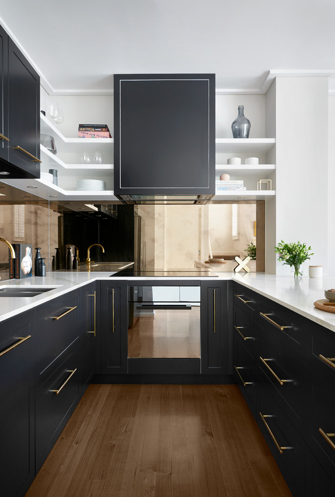 Design ideas for a modern kitchen in Melbourne with mirror splashback, a double-bowl sink, black cabinets, marble benchtops, metallic splashback, stainless steel appliances, light hardwood floors and white benchtop.