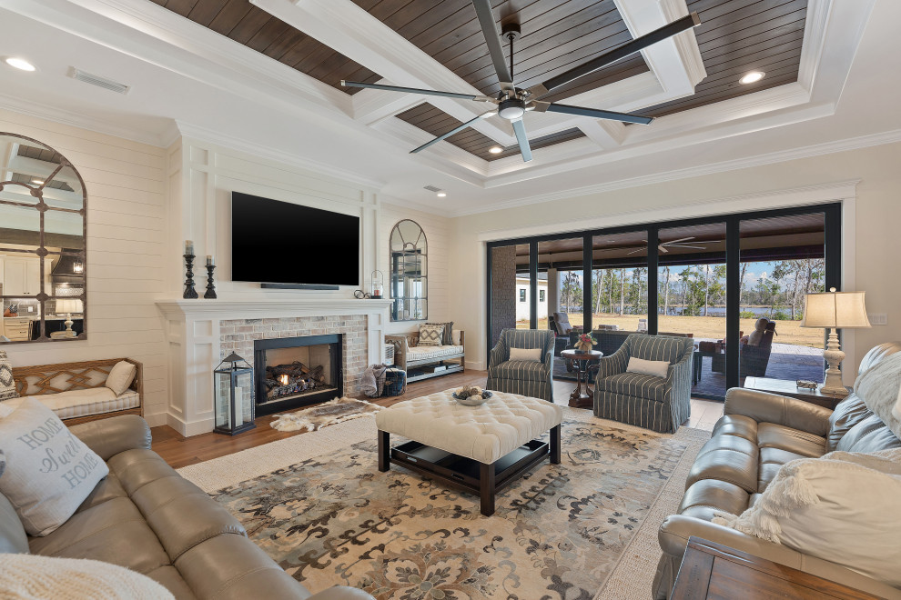 This is an example of a large farmhouse open plan living room in Other with beige walls, medium hardwood flooring, a standard fireplace, a brick fireplace surround, a wall mounted tv, brown floors, a coffered ceiling and tongue and groove walls.
