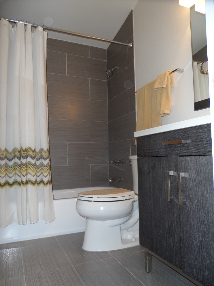 This is an example of a small midcentury bathroom in St Louis with a console sink, flat-panel cabinets, dark wood cabinets, limestone benchtops, a drop-in tub, an open shower, a one-piece toilet, brown tile, porcelain tile, beige walls and porcelain floors.